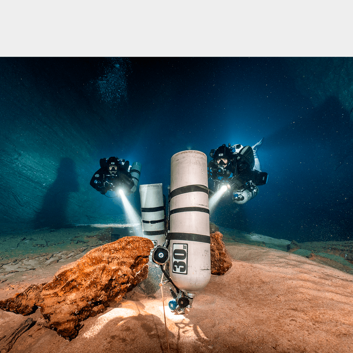 Divers in a cave staged bottles